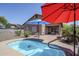 Outdoor view of the pool area and brick patio enhanced by red and blue shade umbrellas at 1813 N Lewis Pl, Casa Grande, AZ 85122