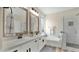 Elegant bathroom featuring dual sinks, framed mirrors, a soaking tub, and a separate tiled shower with glass door at 18371 W Sunrise Dr, Goodyear, AZ 85338
