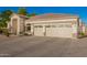 Exterior view of a three-car garage with decorative windows on a home with a neutral color scheme and a tiled roof at 2406 E Oakland St, Chandler, AZ 85225