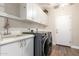 Functional laundry room with modern washer and dryer, cabinets, and utility sink at 2406 E Oakland St, Chandler, AZ 85225