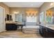 A bathroom features double vanities, a soaking tub, mosaic tile backsplash, and light wood-look tile floors at 2454 W Hope Cir, Chandler, AZ 85248