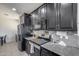 Modern kitchen featuring stainless steel appliances, dark cabinetry, granite countertops, and stylish backsplash tiling at 42180 W Cheyenne Dr, Maricopa, AZ 85138