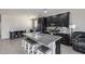 Kitchen featuring island with barstool seating, granite countertops, dark cabinetry, and stainless appliances, open to dining area at 42180 W Cheyenne Dr, Maricopa, AZ 85138