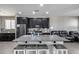 Spacious kitchen island with barstool seating, granite counters, dark cabinets, and stainless appliances in an open-concept area at 42180 W Cheyenne Dr, Maricopa, AZ 85138