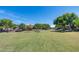 Community park featuring lush green grass, mature trees, and a playground at 42180 W Cheyenne Dr, Maricopa, AZ 85138