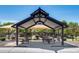 Shaded picnic area with multiple tables and a playground beyond at 42180 W Cheyenne Dr, Maricopa, AZ 85138