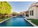 Beautiful backyard featuring a refreshing pool, travertine deck, covered patio, outdoor umbrella, and lush landscaping at 4337 S Helix --, Mesa, AZ 85212