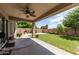 Expansive backyard featuring a covered patio with ceiling fan and lush green lawn at 6657 W Aurora Dr, Glendale, AZ 85308