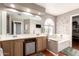 Luxurious bathroom featuring a soaking tub with tile surround, dual sink vanity and an oversized mirror at 6657 W Aurora Dr, Glendale, AZ 85308