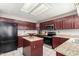 Galley-style kitchen featuring dark wood cabinets, granite countertops, and stainless steel appliances at 6657 W Aurora Dr, Glendale, AZ 85308