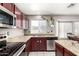 Galley kitchen with stainless steel appliances, granite countertops, cherry cabinets, and tile floors at 6657 W Aurora Dr, Glendale, AZ 85308