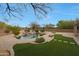 An expansive backyard with lush landscaping, a rock waterfall feature and a fire pit at 6672 E Horned Owl Trl, Scottsdale, AZ 85266
