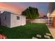 Green backyard with shed, tree, and paver patio under a colorful evening sky at 728 E State Ave, Phoenix, AZ 85020