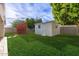 Expansive backyard with a shed and a playhouse surrounded by green grass and trees at 728 E State Ave, Phoenix, AZ 85020