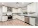 Bright kitchen features white cabinetry, stainless steel appliances, undermount sink, tile backsplash, and light wood floors at 728 E State Ave, Phoenix, AZ 85020