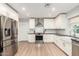 Updated kitchen with white cabinets, stainless appliances, light wood floor, stainless range hood, and undermount sink at 728 E State Ave, Phoenix, AZ 85020