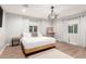 Bright bedroom featuring a king bed, hardwood floors, a unique chandelier, and neutral wall color at 728 E State Ave, Phoenix, AZ 85020