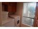 Bright laundry area with washer and dryer, wood cabinets, and a window with light-filtering blinds at 8651 E Royal Palm Rd # 118, Scottsdale, AZ 85258