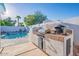 Outdoor kitchen and bar area next to a sparkling swimming pool in a backyard setting at 8716 E Mitchell Dr, Scottsdale, AZ 85251