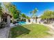 Beautiful backyard with a sparkling pool, lush green lawn, BBQ area, and privacy fence at 9203 S Heather Dr, Tempe, AZ 85284