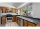 Well-lit kitchen with stainless steel appliances, dark countertops, and wood cabinets at 9203 S Heather Dr, Tempe, AZ 85284