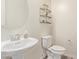 Cozy half bathroom featuring a pedestal sink, toilet, and decorative shelving at 10311 E Trent Ave, Mesa, AZ 85212