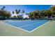 Well-maintained tennis court with a vibrant blue surface, surrounded by lush green trees at 14300 W Bell Rd # 222, Surprise, AZ 85374