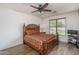 Elegant bedroom features a decorative wooden bed frame, ceiling fan, and a window with natural light at 15140 W Glenrosa Ave, Goodyear, AZ 85395