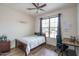 Cozy bedroom featuring wood floors, a ceiling fan, and a window overlooking the front yard at 15140 W Glenrosa Ave, Goodyear, AZ 85395