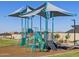 Community playground featuring a shaded play structure with slides, climbing features, and swings amidst a grassy lawn at 17417 W Eva St, Waddell, AZ 85355