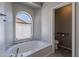 Bright bathroom featuring a soaking tub with decorative tile surround and convenient toilet room access at 1811 E Tierra Buena Ln, Phoenix, AZ 85022