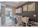 Convenient laundry room with modern washer and dryer, utility sink, and adjacent shoe storage at 1811 E Tierra Buena Ln, Phoenix, AZ 85022