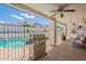 View of the covered patio with a stainless steel grill and a glimpse of the inviting pool behind a safety fence at 1811 E Tierra Buena Ln, Phoenix, AZ 85022