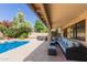 Covered patio area with a cozy seating arrangement, next to the inviting backyard pool and hot tub at 1946 E Caroline Ln, Tempe, AZ 85284