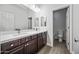 Bathroom with double sink, white countertops and dark wood cabinetry, with a view of the toilet at 20251 W Hadley St, Buckeye, AZ 85326