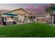 Large backyard features a hot tub, covered patio with dining, and artificial grass for easy maintenance at 2038 N Los Alamos St, Mesa, AZ 85213