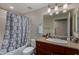 Well-lit bathroom features granite counters, wood cabinets, and shower with decorative patterned shower curtain at 20660 N 40Th St # 1118, Phoenix, AZ 85050