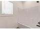 Clean white bathroom offers a tub with shower and window at 2248 S Nikki Ln, Maricopa, AZ 85139
