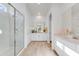 Bright bathroom with glass shower, double vanity, white cabinets, and wood tile flooring at 25338 N 150Th Ln, Surprise, AZ 85387