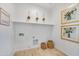 Bright laundry room featuring a storage shelf, woven baskets, light-toned wood-look flooring, and artwork at 25338 N 150Th Ln, Surprise, AZ 85387