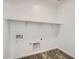Bright laundry room with white walls, wood-style tile flooring, and a built-in shelf for storage at 25338 N 150Th Ln, Surprise, AZ 85387