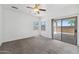 Bright bedroom features neutral carpet, white walls, ceiling fan, and a sliding glass door leading to outdoor patio at 25617 W St James Ave, Buckeye, AZ 85326