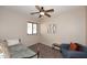 This bedroom includes a bed, blue couch, painting, ceiling fan, and window at 2614 W Fawn Dr, Phoenix, AZ 85041