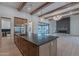 Spacious kitchen featuring an oversized island with stone countertops, stainless steel appliances, and wooden beams at 3950 E Augusta Ave, Queen Creek, AZ 85142