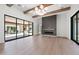 Open living room with a modern light fixture, electric fireplace, and a wall of glass doors leading to the backyard at 3950 E Augusta Ave, Queen Creek, AZ 85142