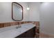 Powder room featuring a wood-framed mirror, globe pendant light, and a sink with dark wood cabinets at 3950 E Augusta Ave, Queen Creek, AZ 85142