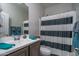 Neutrally-toned bathroom with single sink vanity and shower with striped curtain at 4001 N 300Th Ln, Buckeye, AZ 85396