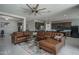 Inviting living room with brown leather sectional, ceiling fan, and open to the kitchen at 4001 N 300Th Ln, Buckeye, AZ 85396
