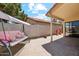 Relaxing covered patio featuring a cozy swing and a beautiful, hardscaped area with lovely potted plants and outdoor access at 4420 E Amberwood Dr, Phoenix, AZ 85048
