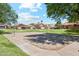 Community sand volleyball court next to an expansive green lawn in a residential area with visible homes and blue skies at 4420 E Amberwood Dr, Phoenix, AZ 85048